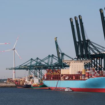 Port of Antwerp, Belgium - 25-05-2023: Large container vessel in the port with wind generators in the background.