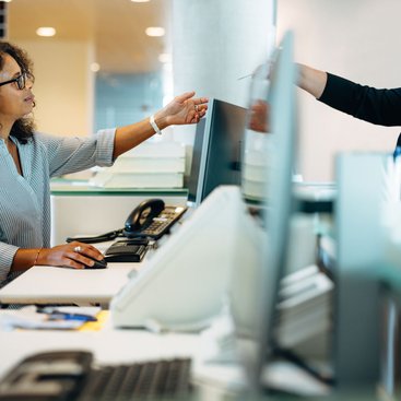 Two women handing over a document across their desks
