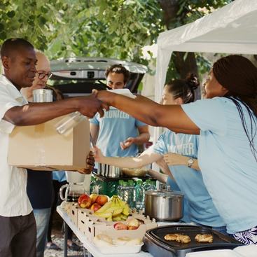 Group distributing contribution boxes to those in need at a homeless and refugee shelter. DC Studio/Shutterstock.